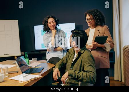 collaborative project troubleshooting session, team members analyze charts and code together friendly Stock Photo