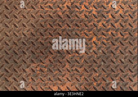 Rusted diamond plate steel surface with repeating industrial tread pattern, suitable for grunge backgrounds, heavy industry themes, and worn metal des Stock Photo