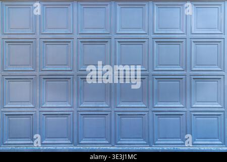 Blue Paneled Garage Door Texture Background. Full frame view of a blue paneled garage door with repeating square sections, clean geometric lines, and Stock Photo