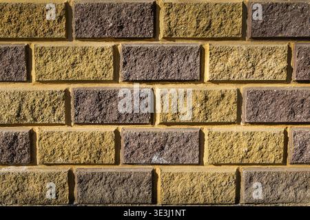 Yellow and Brown Brick Wall Texture Background. Full frame close-up of a yellow and brown brick wall with rough surface and mortar lines, ideal as a Stock Photo