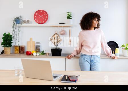 Thoughtful woman looking out window relaxing in kitchen from working at home Stock Photo