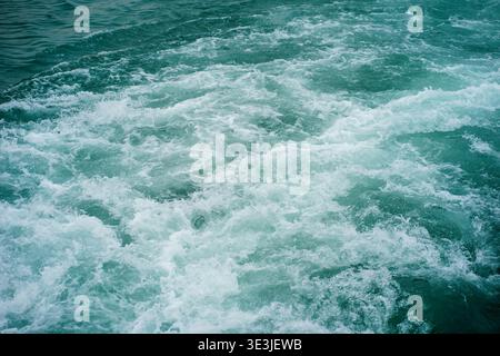 Turquoise foamy water wake texture on lake surface, dynamic motion background with splashing waves, bubbles and swirling aquatic pattern Stock Photo