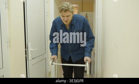 Elderly man using a walker to move through a doorway at home Stock Photo
