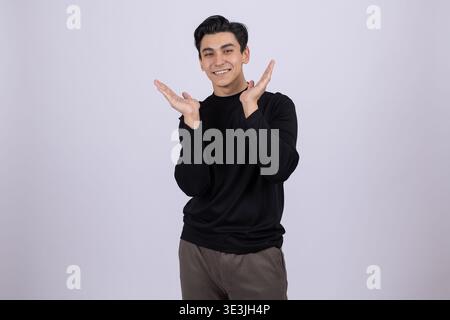 Cheerful young man posing with hands on his face in studio Stock Photo