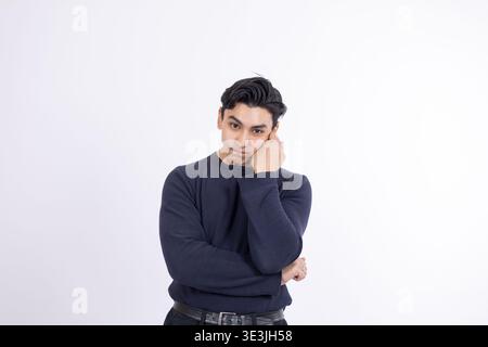 Tired young man leaning on his hand with a bored expression Stock Photo