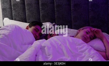 Young couple sleeping together in a bed on white background Stock Photo
