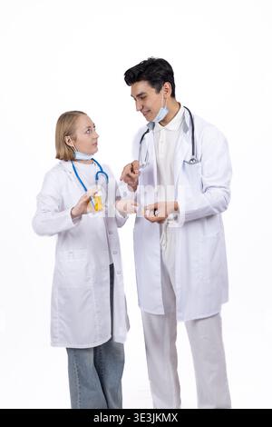 Two medical doctors in white coats talking in a studio setting Stock Photo