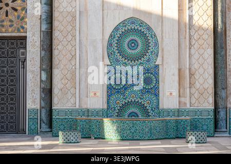 Ornate Moroccan mosaic tile panel on a mosque exterior in Casablanca, featuring intricate geometric patterns, blue and green ceramic tiles, carved sto Stock Photo