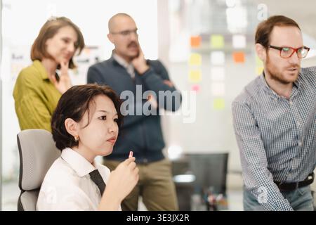 Businesspeople collaborate in a modern workspace, discussing strategies while analyzing data trends and brainstorming solutions to improve project Stock Photo