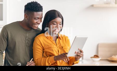 Happy Black Spouses Using Digital Tablet While Cooking Lunch In Kitchen Together Stock Photo