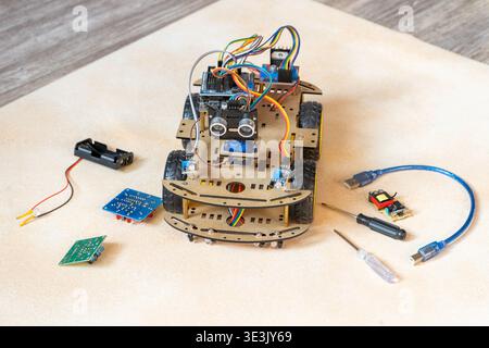 DIY robotic car kit with ultrasonic sensor, controller. Educational electronics project for STEM learning and robotics. Robot Assembly With Electronic Components. Stock Photo