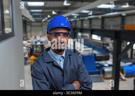 An African American male engineer works in an industrial facility using technology to oversee production workflows and processes. Stock Photo