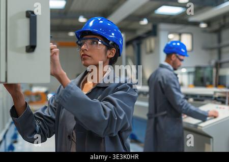 Team of engineers works together in a factory, using technology while focusing on production tasks and problem-solving. Stock Photo
