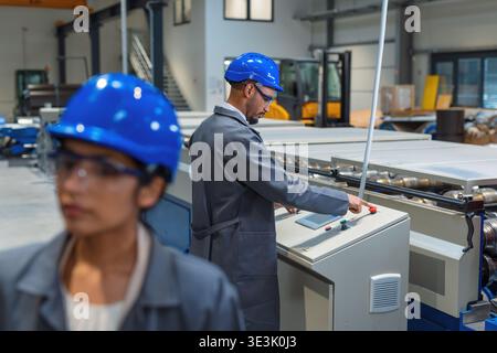 Team of engineers works together in a factory setting managing production tasks with modern equipment and tools. Stock Photo