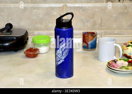 A blue water thermos stands on the kitchen table. Stock Photo