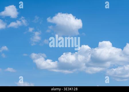 Bright blue sky filled with fluffy white clouds, varying in size and shape, creating a serene and tranquil scene. The clouds are well-defined against Stock Photo