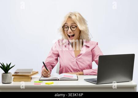 Woman Studying and Smiling While Taking Notes at a Desk During the Day Stock Photo