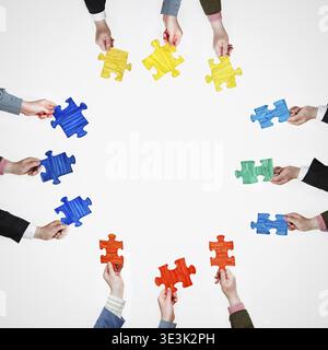 Place painted puzzle pieces in human hands on four sides on a gray background Stock Photo