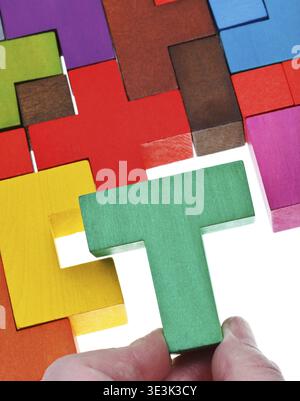 Place a T-shaped piece individually on a white background in a multi-colored wooden puzzle Stock Photo