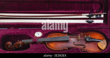 Old wooden violin with bow in red velvet case Stock Photo