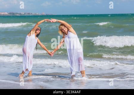Happy Mature Women Making Heart Shape Together in Sea Stock Photo
