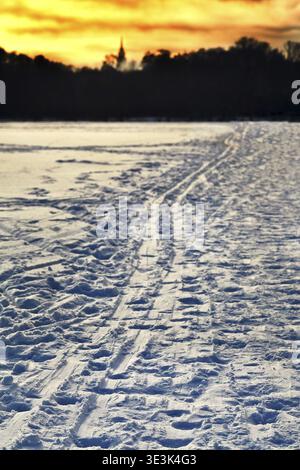 Cold yellow winter sunset over ski slopes in snowy fields Stock Photo