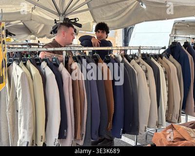 Porta Portese flea market stalls. Two young men browse men's tailored blazers and casual jackets at the famous Sunday market in Rome, Italy. Stock Photo