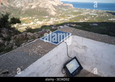 Small solar panel powering light on church wall near Leonidio, Greece Stock Photo