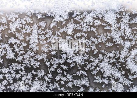 Snowflakes and frost patterns on window panes on cold winter evenings Stock Photo