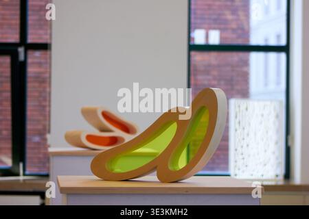 Two abstract contemporary sculptures displayed on white pedestals in a bright gallery space with large windows. The foreground sculpture features a Stock Photo