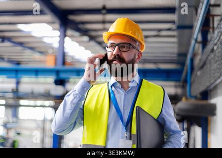 Warehouse manager with safety helmet making phone call. Stock Photo