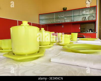 A dining table is set with bright chartreuse yellow-green tableware including lidded serving dishes, teapots, cups, and plates arranged on an ornate Stock Photo