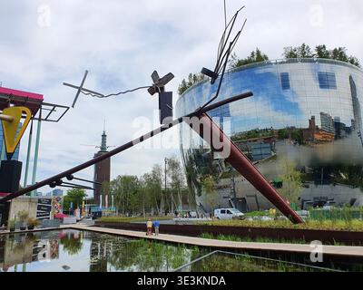 An outdoor view of the Museumpark in Rotterdam featuring a large abstract metal sculpture installation with intersecting dark beams and Stock Photo