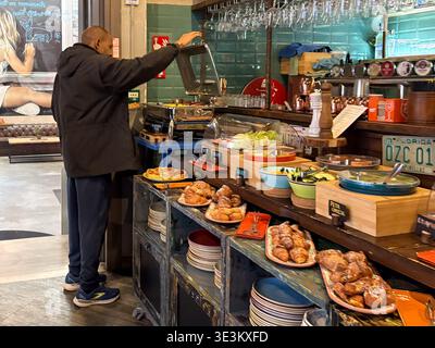 Hotel buffet breakfast spread with pastries and salad options in Rome, Italy. Guest selecting food items. Stock Photo