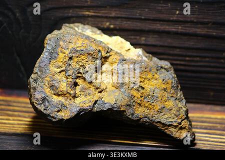 Rough limonite iron ore specimen from Russia's Kaluga region, showcasing rich earthy tones and rugged texture against dark wood Stock Photo
