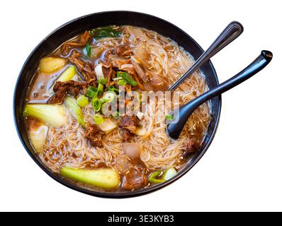 Deep clay bowl is filled with hot noodle soup and veal fillet. Stock Photo
