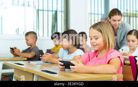 Pupils using mobile phones during lesson in school Stock Photo