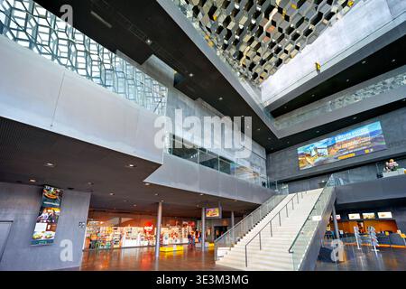 Visitors walk through the Harpa Opera House in Reykjavik. The unique architecture features large windows and a spacious interior. Stock Photo