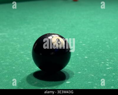 A close-up of a billiard table with a lone black eight ball on vibrant green felt, showcasing the ball arrangement and textures in a game-focused atmo Stock Photo