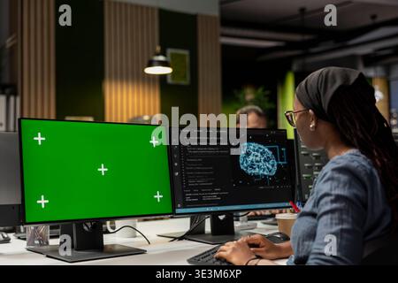 Programmer utilizing AI software on green screen PC to optimize performance and forecast issues. IT specialist in tech startup office training machine learning models using chroma key computer Stock Photo