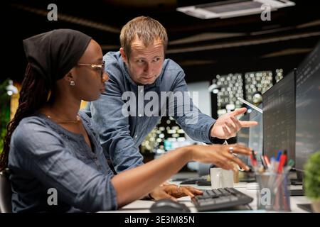 Team of programmers in tech startup office develop apps using AI machine learning automation. Coworkers working on PC, debugging applications with artificial intelligence Stock Photo