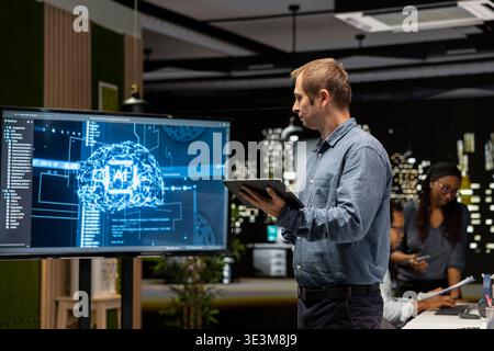 System administrator machine learning APIs developed by interns. Tech company team leader looking at large screen in tech startup to troubleshoot software errors using artificial intelligence Stock Photo