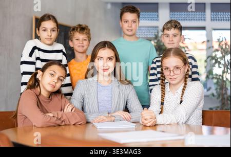 Group photo of teacher and preteen schoolchildren in classroom Stock Photo