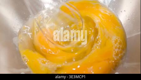 Whisking eggs in a glass bowl for cooking or baking during a home kitchen activity Stock Photo