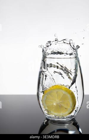 Lemon Slice Splashing into Glass of Water – Fresh Citrus Motion Shot Stock Photo