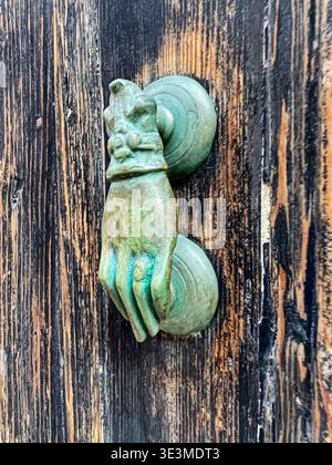 An old bronze door knocker in the shape of a hand is ready to announce visitors in the old town of Chania on Crete. Stock Photo
