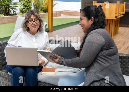 Two women exchanging ideas and notes during a casual outdoor meeting Stock Photo