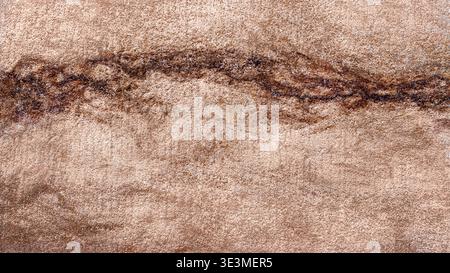 Abstract textured background featuring warm beige and brown tones with subtle variations and a wavy dark line running horizontally across the surface Stock Photo