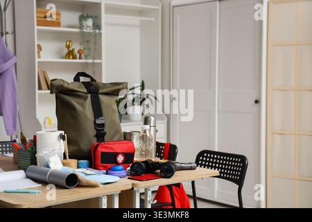 School desks with emergency backpack, first aid kit and necessities in classroom Stock Photo