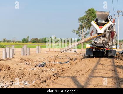 Industrial construction site scene with a crew working together to pour and level fresh concrete for a new building structure. Stock Photo